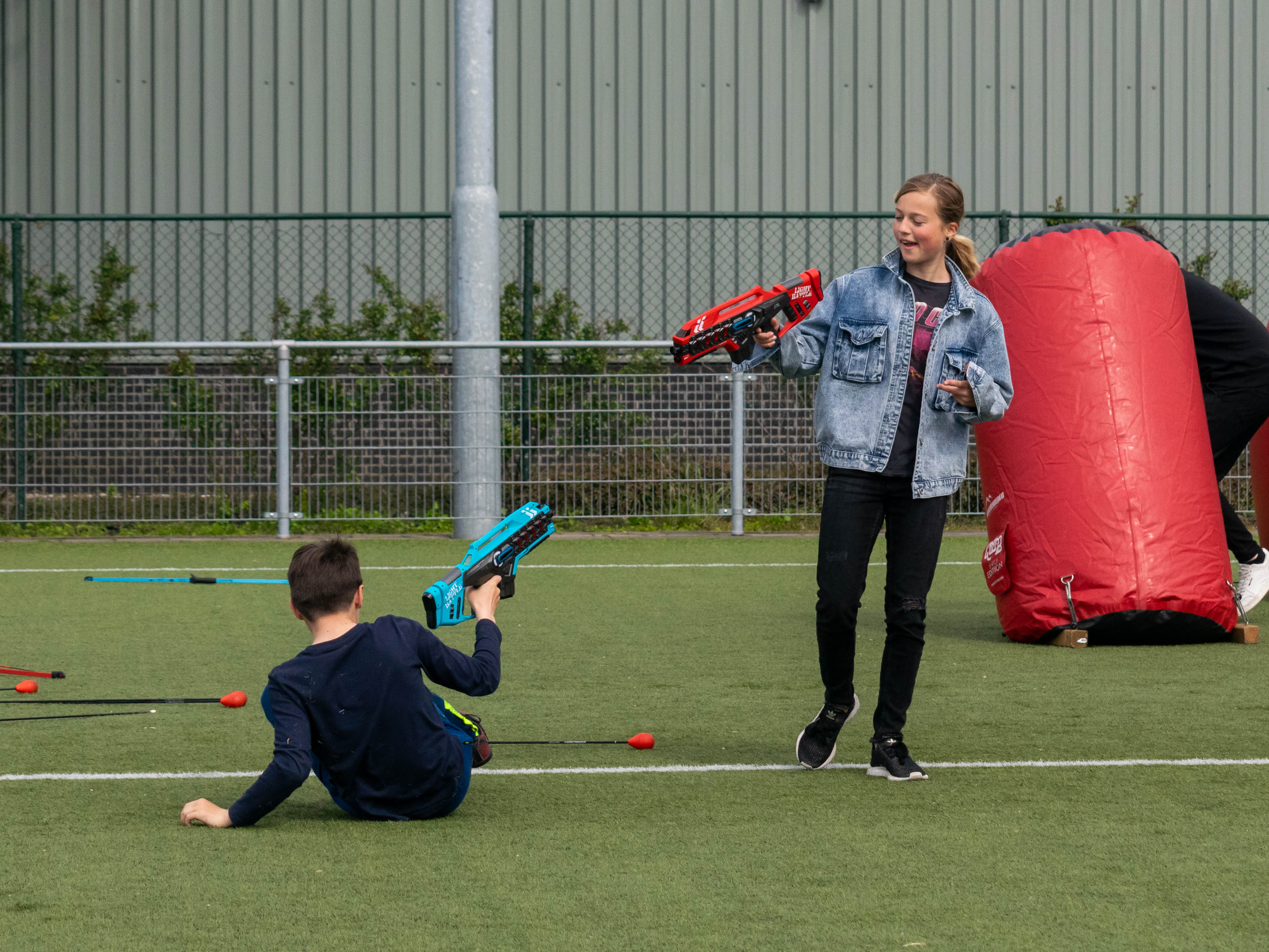 Zelf op locatie buiten lasergamen met twee kinderen bij een obstakel met laserguns