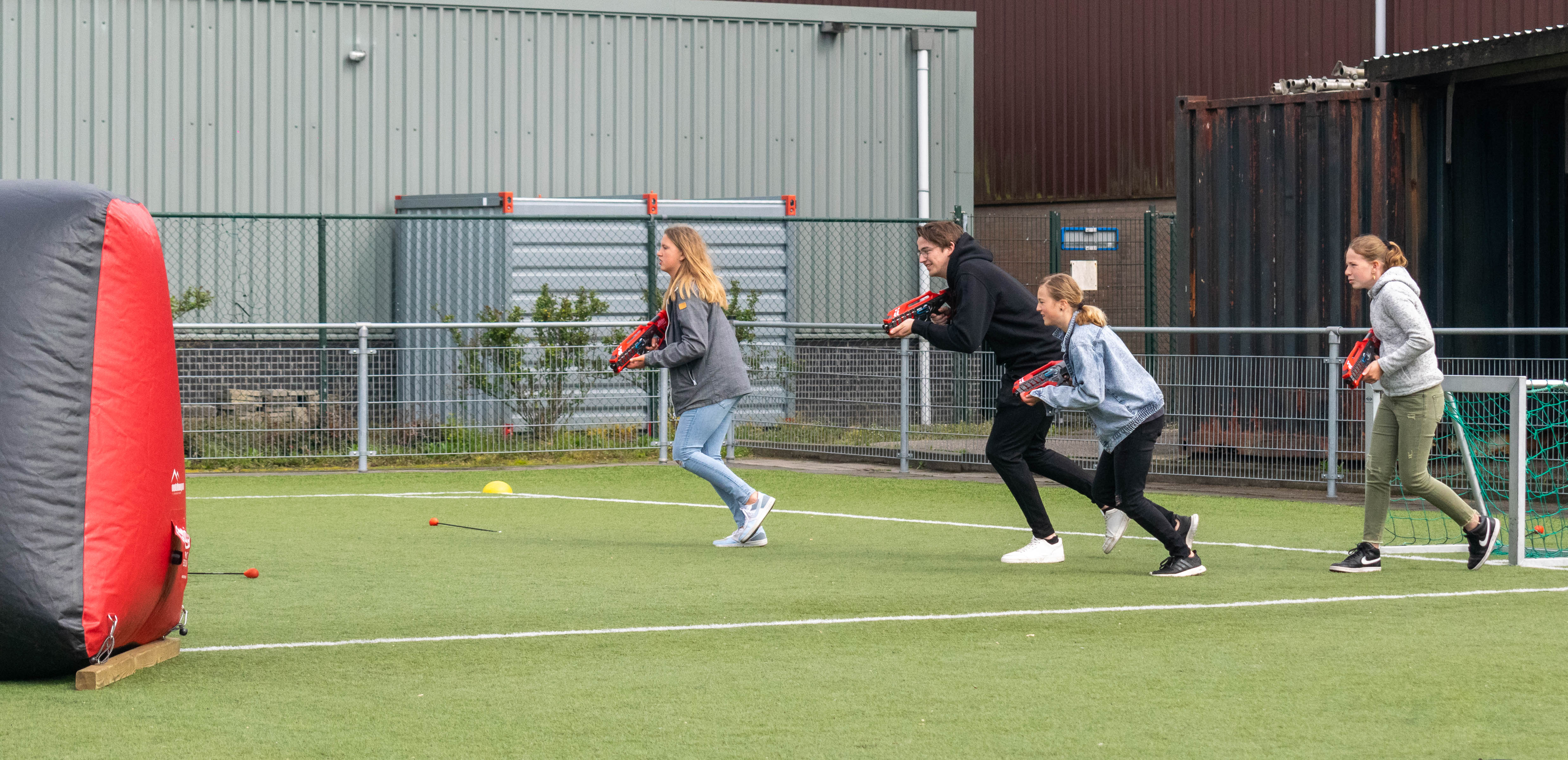 Wat is lasergamen vier vrienden die buiten lasergame spelen op een grasveld met obstakels
