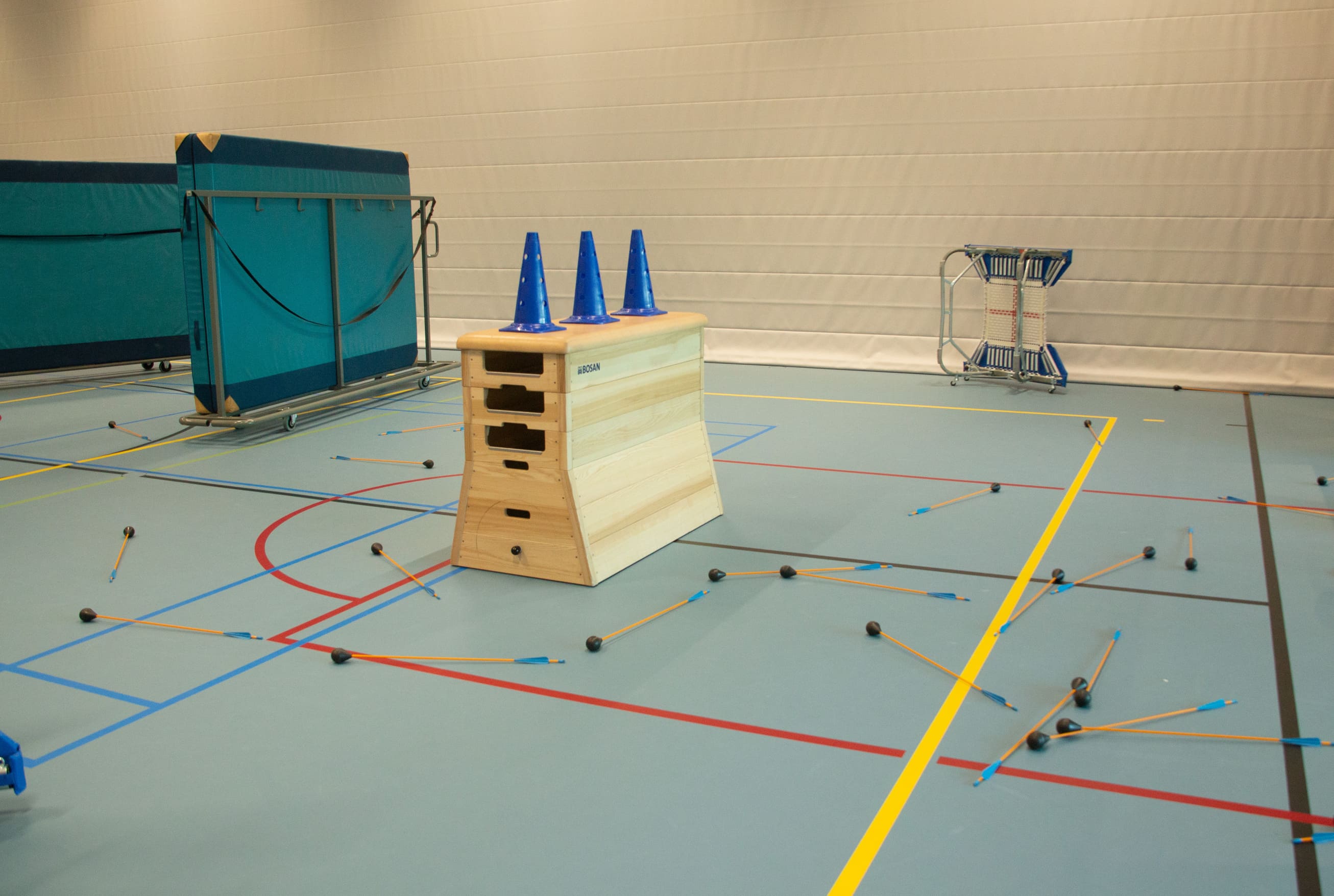 Archery tag indoor opgebouwd met matten en attributen in een gymzaal voor sfeer