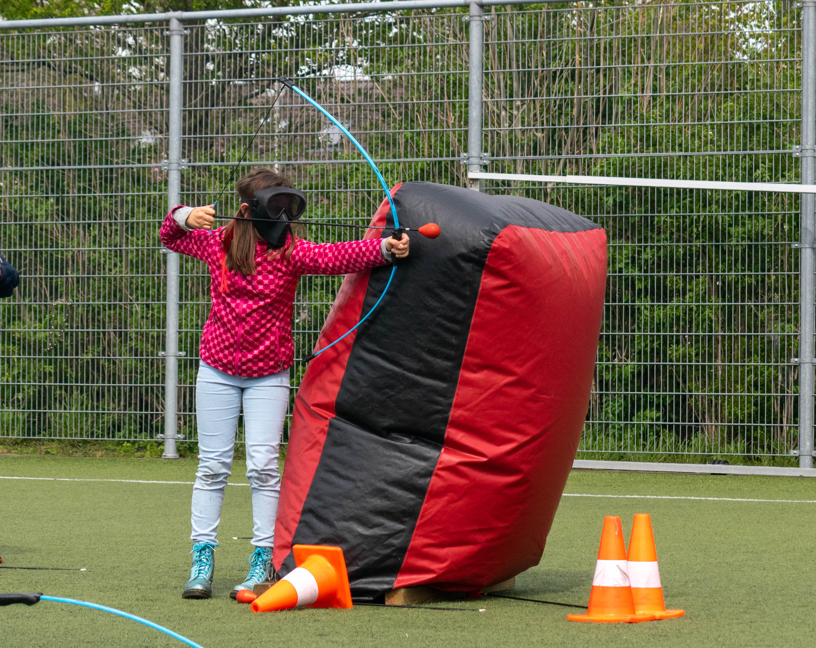 Kinderen met een beschermend masker en een boog met foam pijlen tijdens een archery tag kinderfeestje