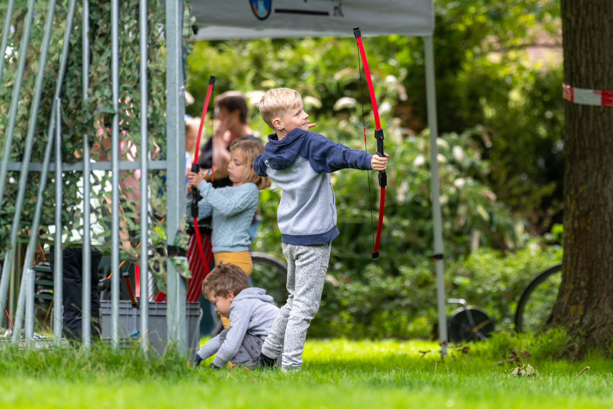 Kinderen met een beschermend masker en een boog met foam pijlen tijdens een archery tag kinderfeestje