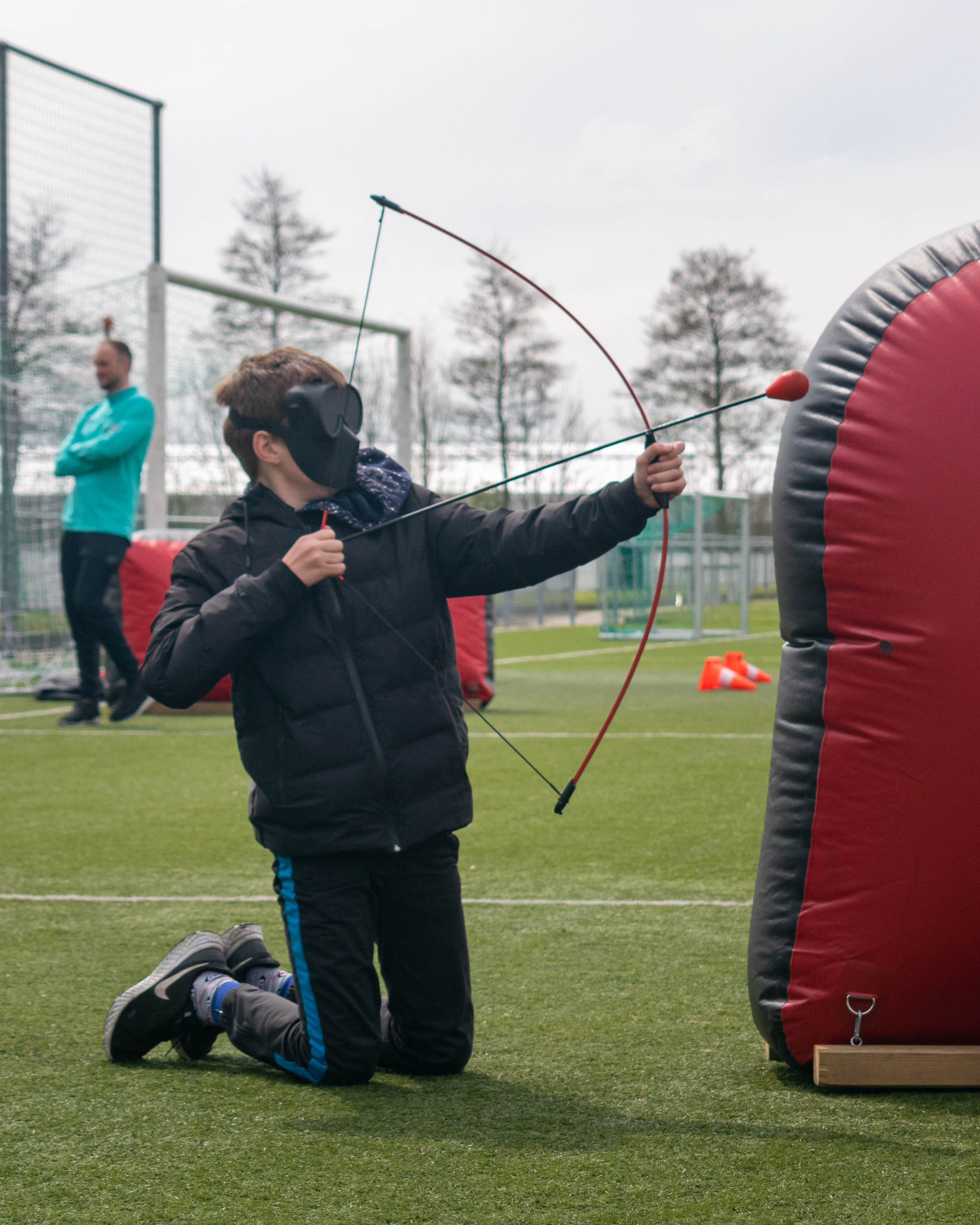 Wat is archery tag een kind spant een pijl en boog buiten op een sportveld