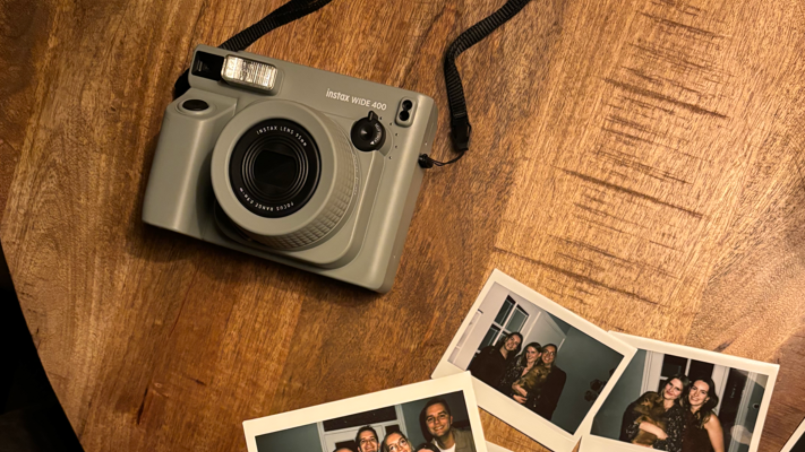 De Fujifilm Instax Wide 400 polaroid camea met een aantal foto's op breed fotopapier
