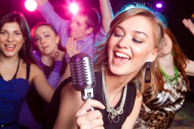 Karaoke thuis zelf huren de beste tips een vrouw zingt in een microfoon met vrienden