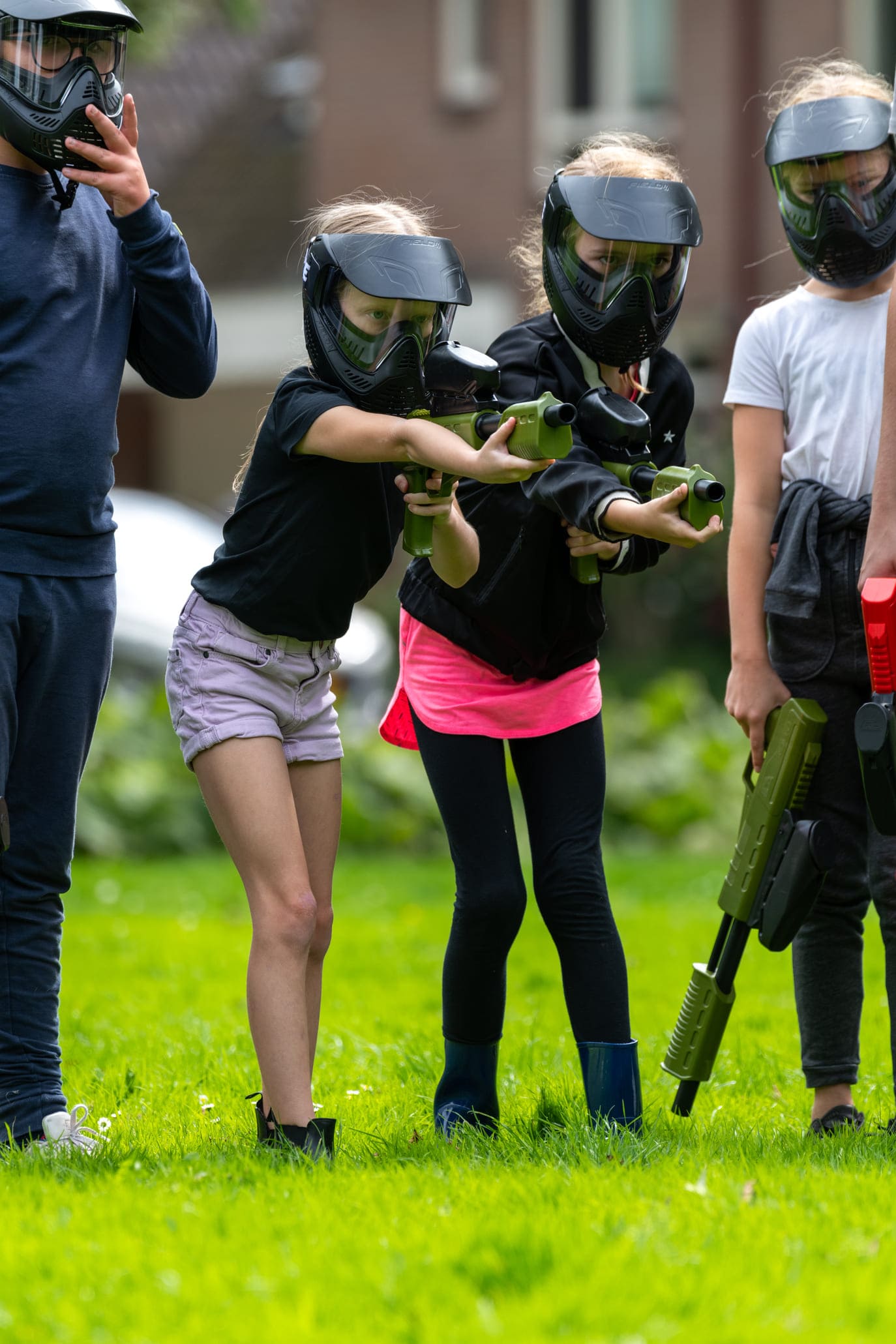 Paintball kinderfeestje organiseren tips met een groep kinderen op een grasveld paintballen