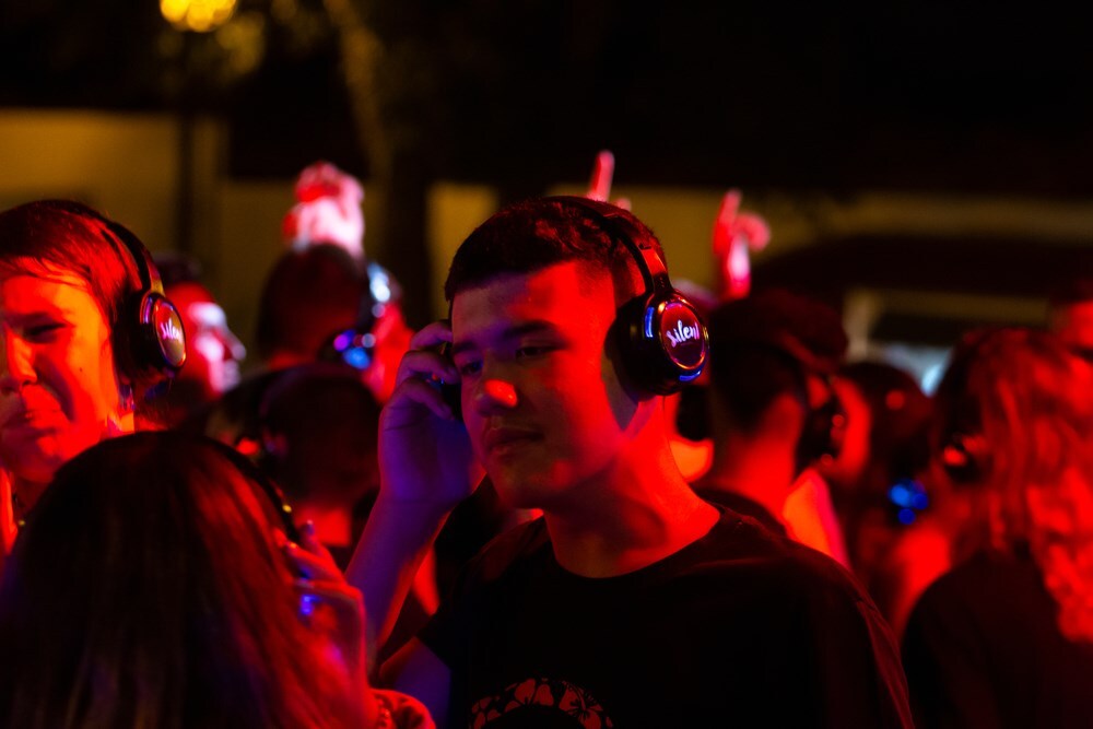Silent disco thuis organiseren met koptelefoon mensen die dansen onder rode verlichting club feestje